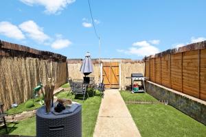 a small garden with a fence and a table and a umbrella at The Spacious Gem House Kent with Parking in Gillingham