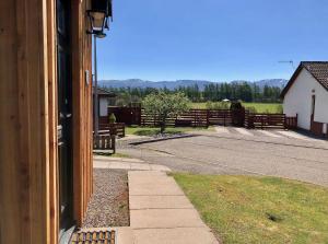 an open door of a house with a road and a fence at Blaeberry Cottage in Aviemore