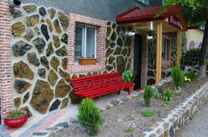 a red bench sitting in front of a building at Guest house poligloti in Tʼelavi