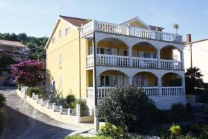 a large yellow house with a white balcony at Apartmen Karmen 2 in Trogir