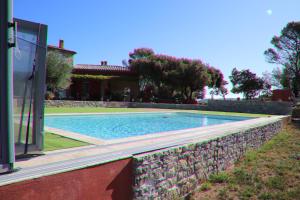 a swimming pool with a stone wall next to a house at LA BASTIDE DE NINI in Carcès
