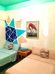 - une chambre avec 2 lits, une table et un tableau dans l'établissement MEDUSA'S HOSTEL, à Aguadilla