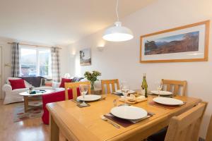 a dining room with a table and a living room at Blaeberry Cottage in Aviemore