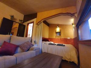 um quarto com uma cama, um sofá e um espelho em Casa Rural El Retiro, rural loft em Buenache de la Sierra