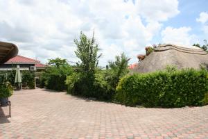 a patio with a thatch roof and some bushes at Honeybed Lodge in Lusaka