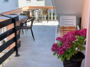 een balkon met een tafel en stoelen en paarse bloemen bij Apartman Vodice in Vodice