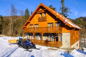 a log cabin with a snowmobile parked in the snow at Apartmány Valča in Valča