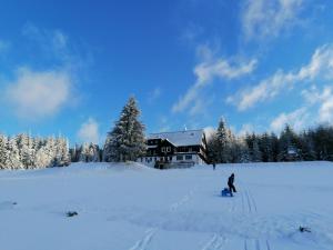 a person skiing in the snow in front of a house at chata Karolínka in Benecko