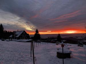 a house in the snow with the sunset in the background at chata Karolínka in Benecko