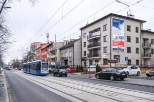 Un autobús azul conduciendo por una calle de la ciudad con coches en Bronowicka Premium Apartment - 52m2 with private parking, en Cracovia