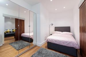 een slaapkamer met een bed en een glazen wand bij Oxford Circus Luxury Holiday Let in Londen