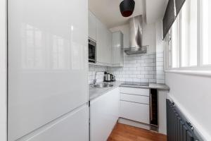 a white kitchen with a sink and a window at Oxford Circus Luxury Holiday Let in London