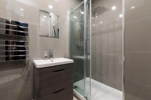a bathroom with a sink and a glass shower at Oxford Circus Luxury Holiday Let in London