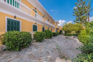 a house with yellow walls and a stone walkway at Capriccio Studios in Argassi