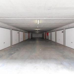 a large empty garage with white doors and a large floor at Zeedijk 68 in Blankenberge