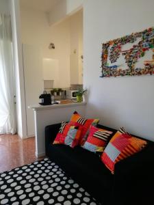 uma sala de estar com um sofá preto com almofadas coloridas em Le stanze di Ninni em Foligno