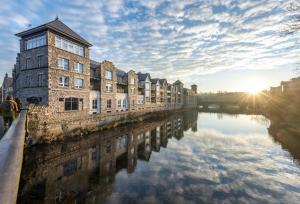 una fila de edificios junto a un río con la puesta de sol en Luxury riverside apartment in Kendal, en Kendal