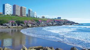 a beach with some rocks and buildings and the ocean at Frente al Mar y Casino - La mejor ubicacion en Mar del Plata in Mar del Plata