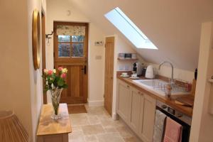 una cucina con un vaso di fiori su un tavolo di The Old Doctors Retreat- Near Soho Farmhouse a Sandford Saint Martin