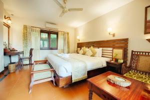 Greenwoods Resort, Thekkady في تيكادي: غرفة نوم بسرير ابيض كبير وطاولة