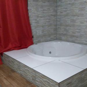a bath tub in a bathroom with a red curtain at Pousada Leal Chalé in Visconde De Maua