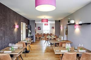 a restaurant with wooden tables and chairs and pink lights at LA GLORIETTE in Marche-en-Famenne