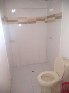 a white bathroom with a toilet in it at Tadù Playa Hotel in San Bernardo del Viento
