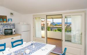 cocina con mesa con sillas azules y balcón en Appartamento BluMare en Santa Maria Navarrese