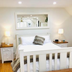 a bedroom with a white bed with a mirror at Aldgate Creek Cottage Bed and Breakfast in Aldgate