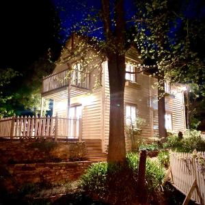 ein weißes Haus mit einer Veranda und einem Baum in der Nacht in der Unterkunft Aldgate Creek Cottage Bed and Breakfast in Aldgate