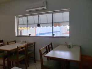 ein Esszimmer mit zwei Tischen und einem Fenster in der Unterkunft Hotel Flamboiã in Araraquara
