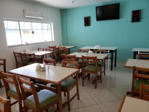 una sala da pranzo con tavoli, sedie e TV a schermo piatto di Hotel Flamboiã ad Araraquara