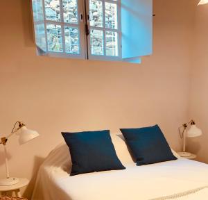a bedroom with a bed with blue pillows and a window at Casas de Mértola 33 in Mértola