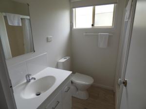 a white bathroom with a sink and a toilet at Grassy Head Holiday Park in Stuarts Point