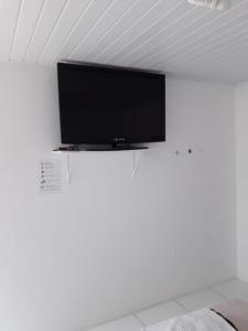 a flat screen tv hanging on a white wall at Pouse Bem in Blumenau