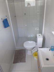 a white bathroom with a toilet and a shower at Pouse Bem in Blumenau