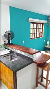 een keuken met een wastafel en een blauwe muur bij casa em condomínio com piscina in Maresias