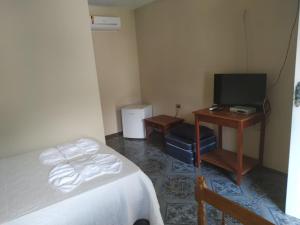 a bedroom with a bed and a desk with a television at Estalagem São Gonçalo in Tarituba