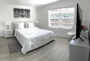 a white bedroom with a large bed and a television at Modern Home, Excellent Location Miami in Miami
