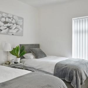 a bedroom with two beds and a flower painting on the wall at Priory Suites in Liverpool