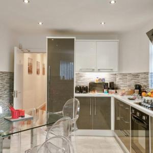 a kitchen with white cabinets and a glass table and chairs at Priory Suites in Liverpool