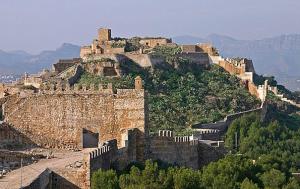 a large castle on top of a hill with trees at playa y relax valencia in Puerto de Sagunto