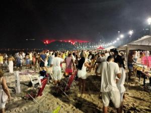 een grote menigte mensen op het strand 's nachts bij Ótimo Conjugado - Estúdio - Praia do Flamengo - RJ in Rio de Janeiro