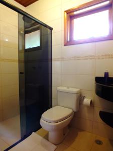 uma casa de banho com um WC, um chuveiro e uma janela. em Pousada Vista da Serra Monte Verde em Monte Verde