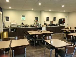 a restaurant with tables and chairs and a kitchen at SureStay Plus Hotel by Best Western Southern Pines Pinehurst in Southern Pines