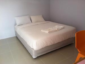 Una cama con sábanas blancas y una toalla. en Pak Dee Resort, en Nakhon Ratchasima