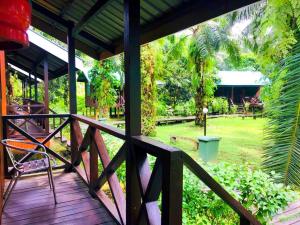a wooden porch with a chair and a yard at Sukau Backpackers B&B in Sukau