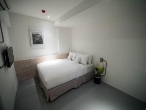 a small bedroom with a bed with white sheets at King Wow Inn in Tainan