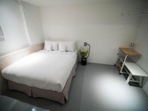 a small room with a bed and a desk at King Wow Inn in Tainan