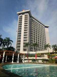 Century Park Hotel في مانيلا: مبنى كبير أمامه مسبح